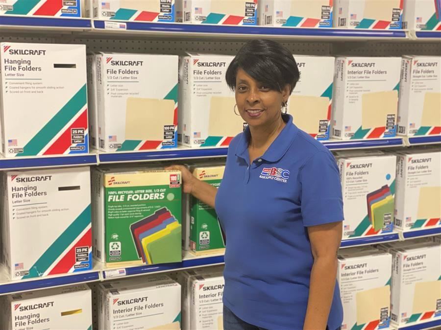  Charissa Archield smiles to camera in front of products at the Anniston Army Depot. 